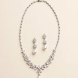 A necklace and earrings set made of white pearls and diamonds, arranged on a light-colored background.