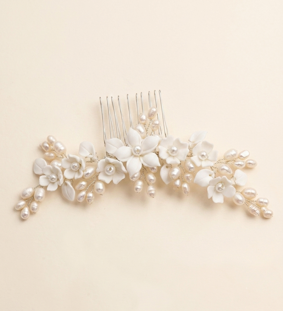 A decorative hair comb with white flowers and pearls on it.