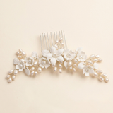 A decorative hair comb with white flowers and pearls on it.