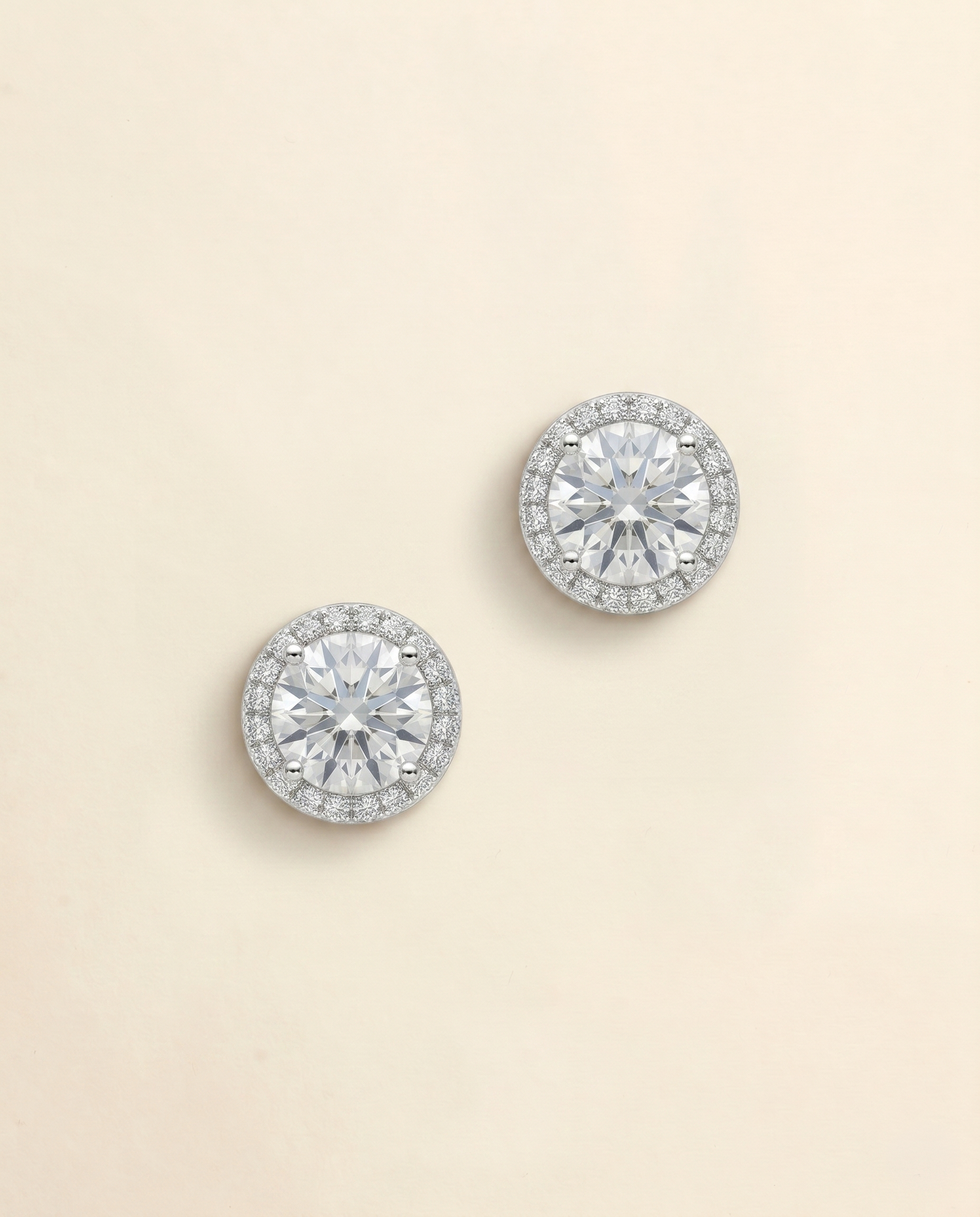 A pair of elegant diamond earrings with a large central diamond surrounded by smaller diamonds, set in a halo of smaller diamonds.
