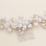 A decorative hair comb with white flowers and pearls attached to it.