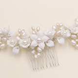 A decorative hair comb with white flowers and pearls attached to it.