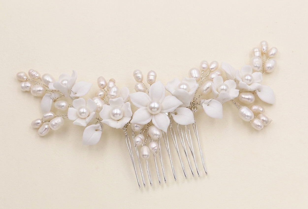 A decorative hair comb with white flowers and pearls attached to it.