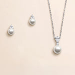 A necklace and earrings set made of silver and white pearls, with a pendant featuring a large round pearl and smaller pearls.
