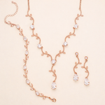 a delicate and elegant necklace and earring set, featuring a delicate chain with small, clear gemstones and a pair of dangling earrings with similar clear gemstones.