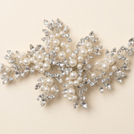 A decorative piece of jewelry with a combination of pearls, crystals, and leaves.