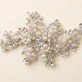 A decorative piece of jewelry with a combination of pearls, crystals, and leaves.