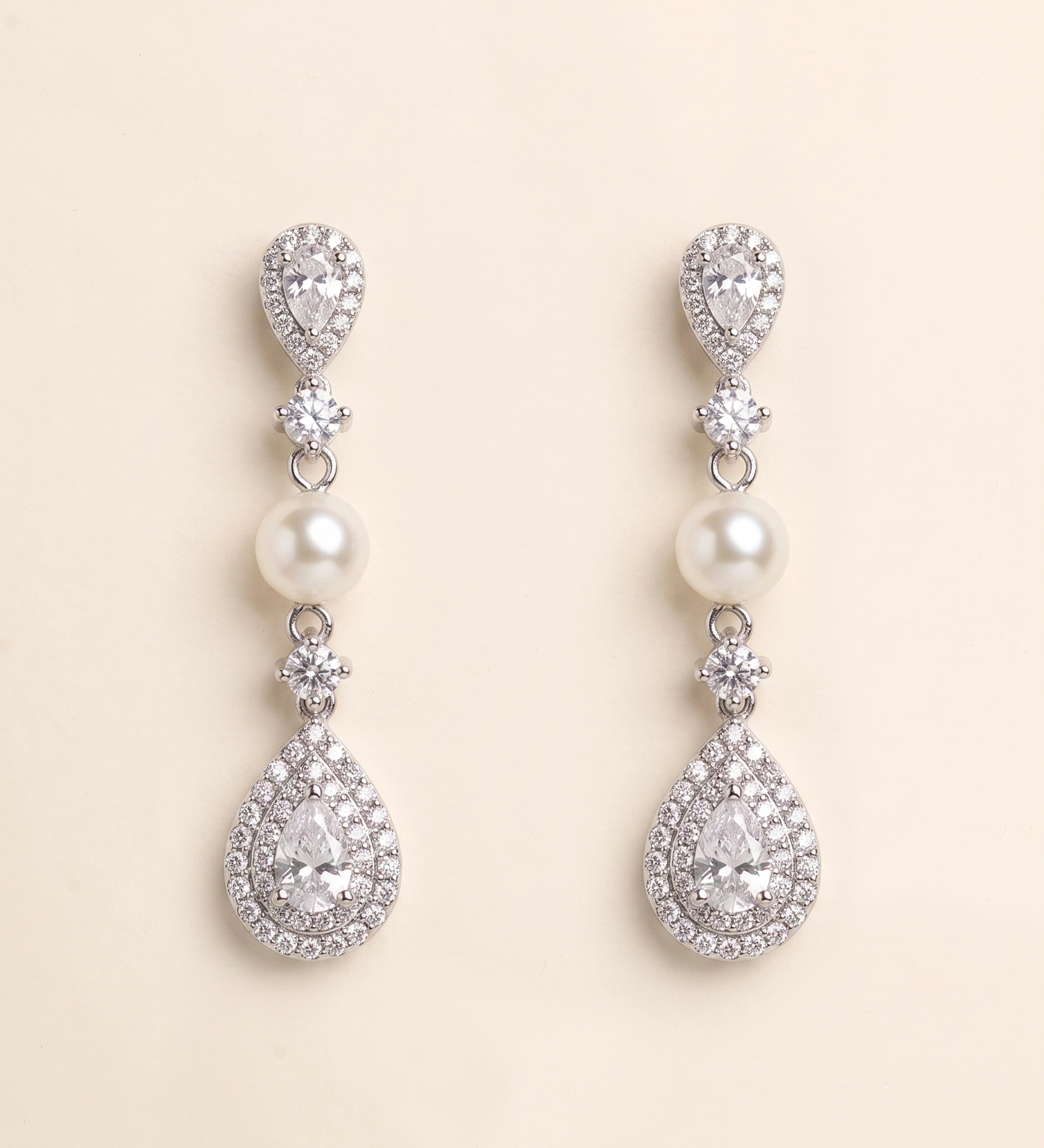 A pair of elegant earrings with pearls and diamonds, set against a light beige background.