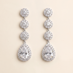 A pair of elegant earrings with a row of small, round diamonds set in a halo around the center of each large, pear-shaped gemstone.
