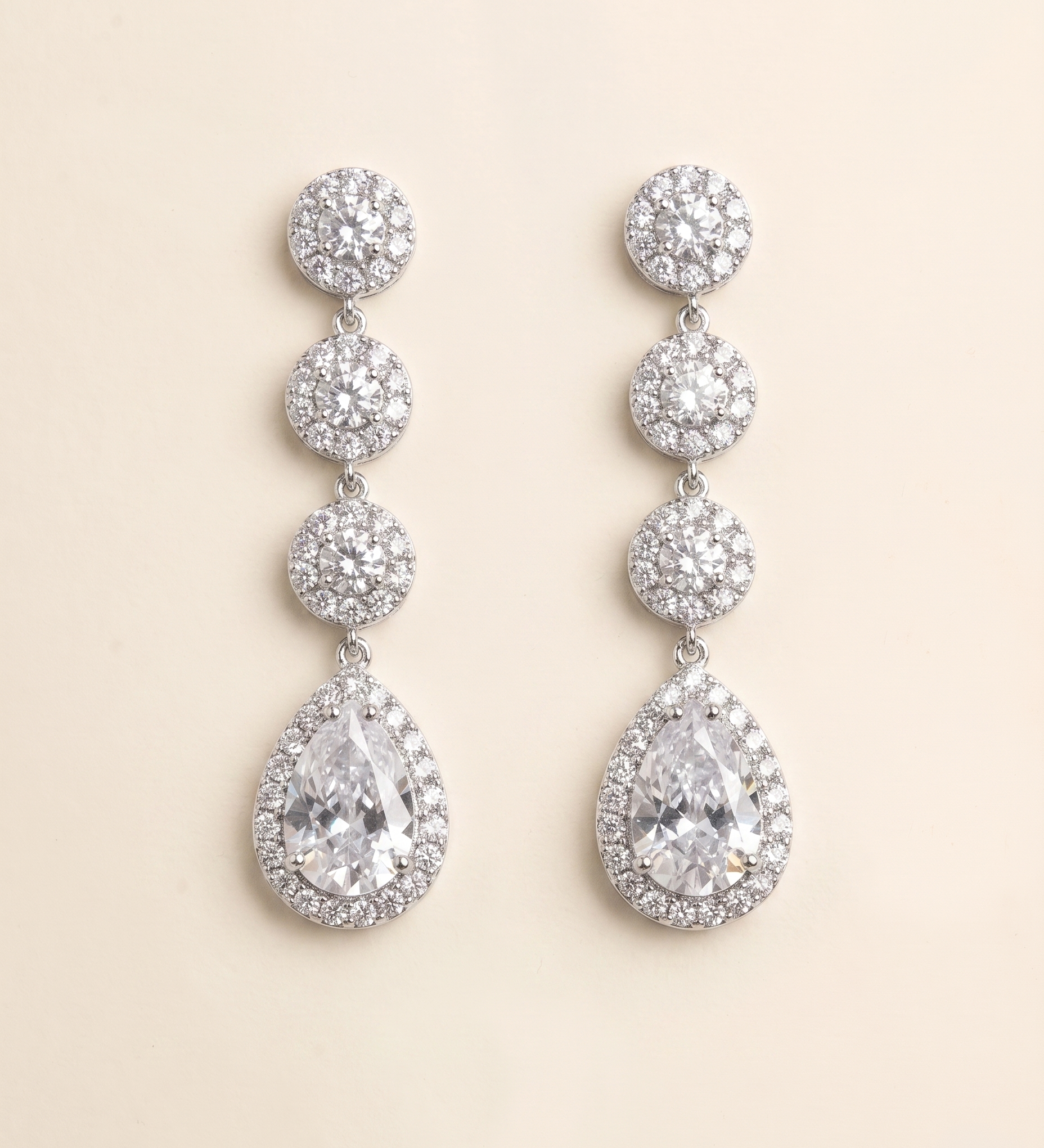 A pair of elegant earrings with a row of small, round diamonds set in a halo around the center of each large, pear-shaped gemstone.