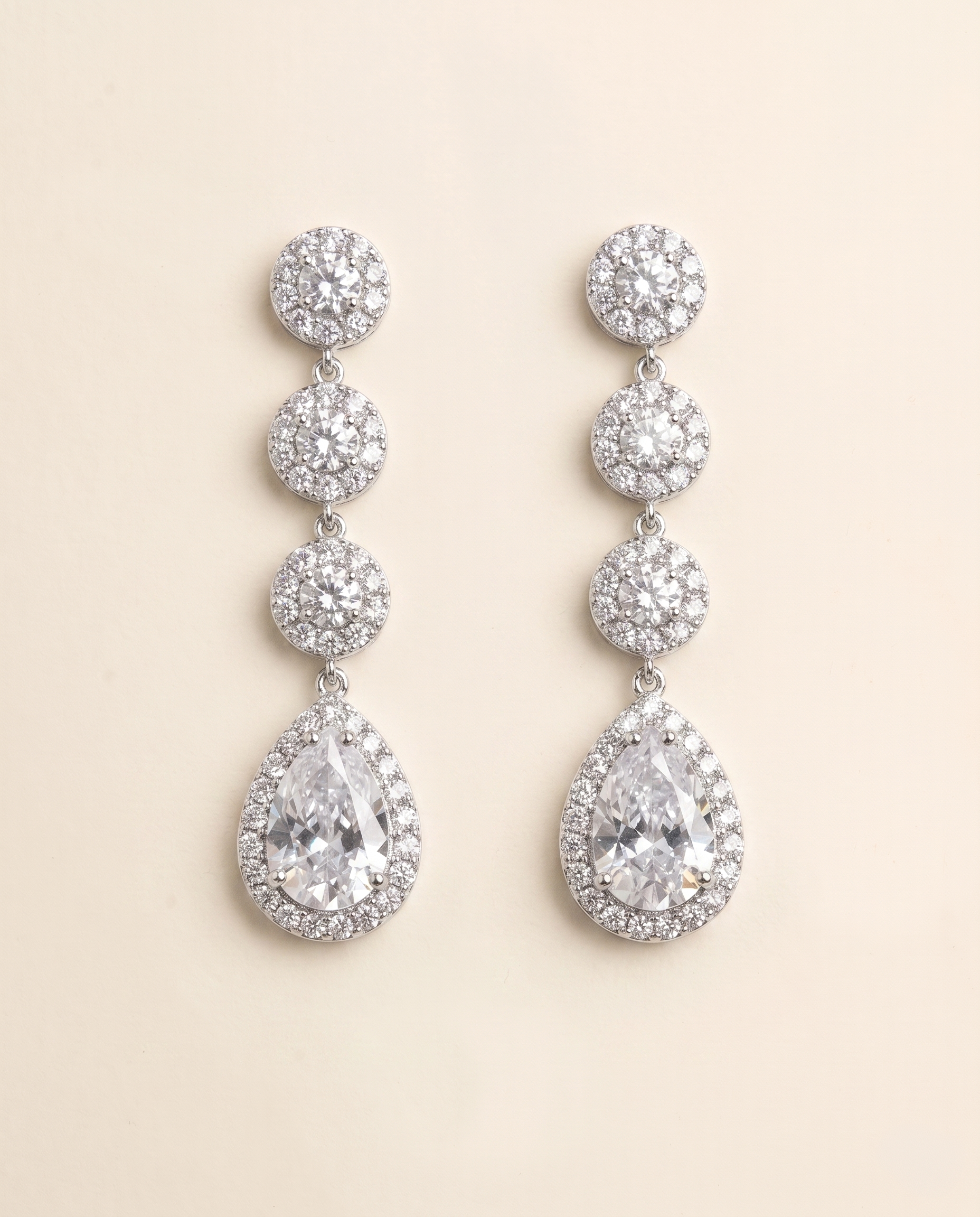 A pair of elegant earrings with a row of small, round diamonds set in a halo around the center of each large, pear-shaped gemstone.