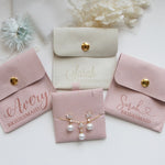 a collection of jewelry and accessories, including earrings, a necklace, and a bridesmaid's bag, all arranged on a white background.