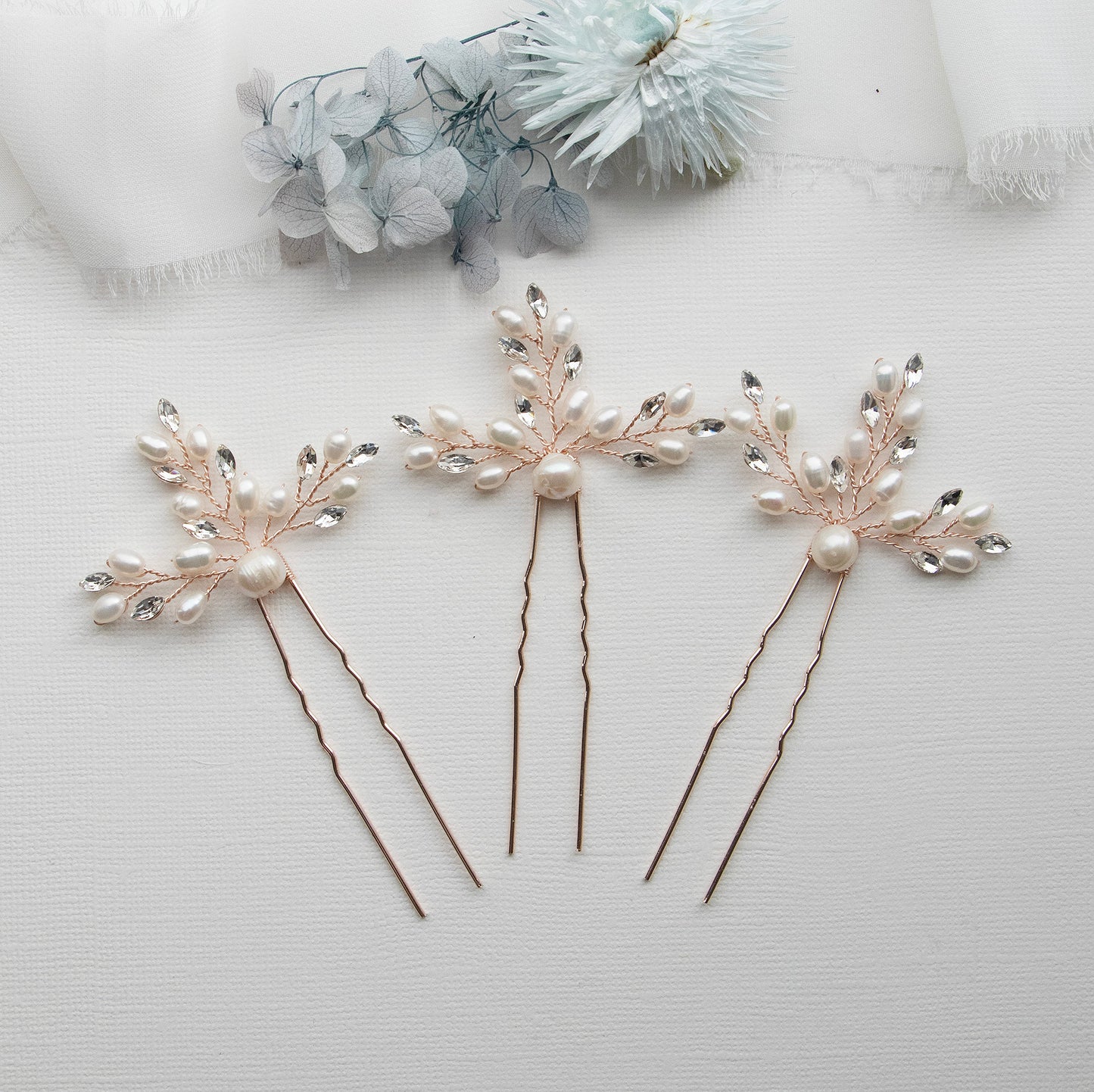 three hair pins with flowers and pearls on them