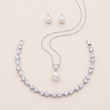 A necklace, earrings, and a pendant set against a light beige background.