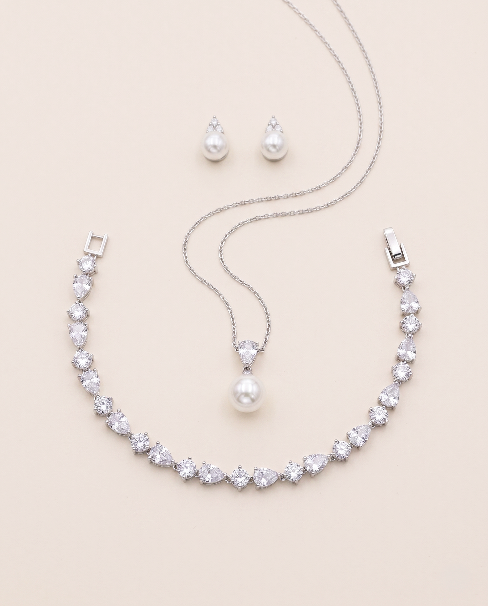 A necklace, earrings, and a pendant set against a light beige background.
