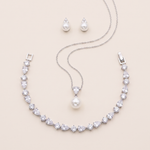 A necklace, earrings, and a pendant set against a light beige background.