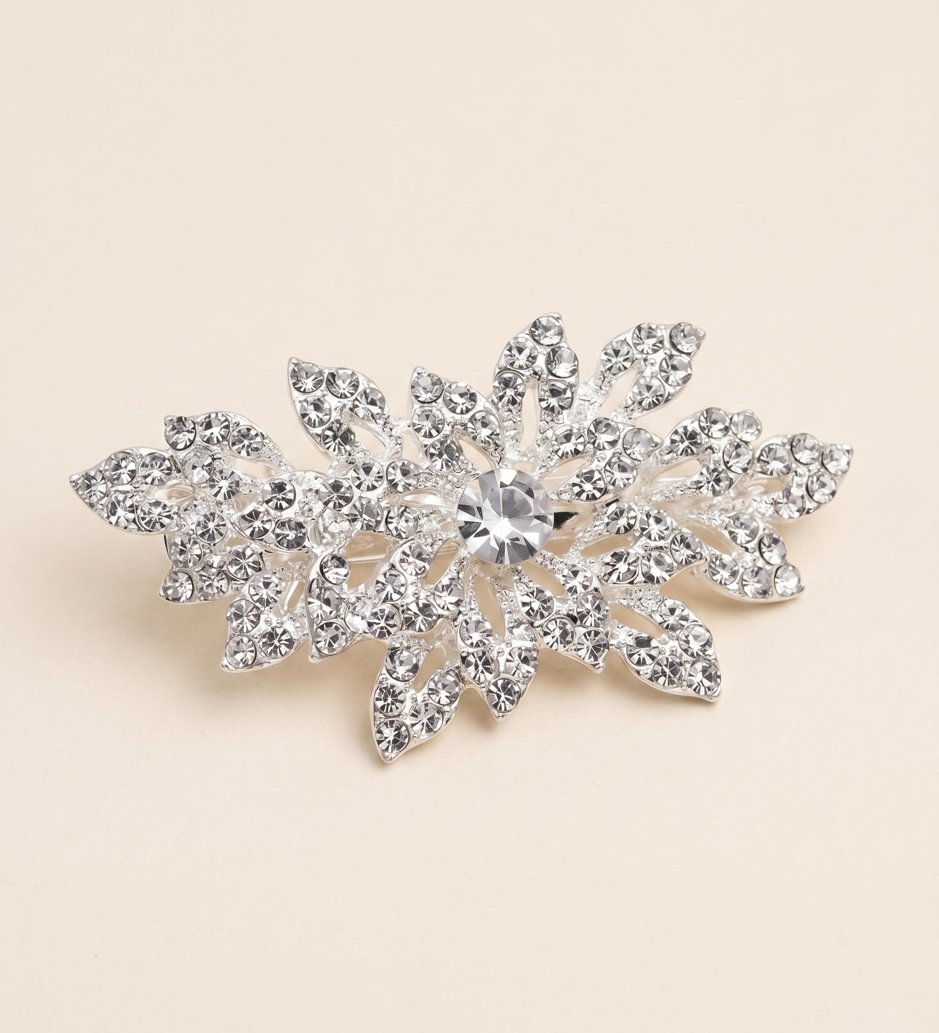 A sparkling crystal brooch with a central stone surrounded by intricate leaf-like designs.