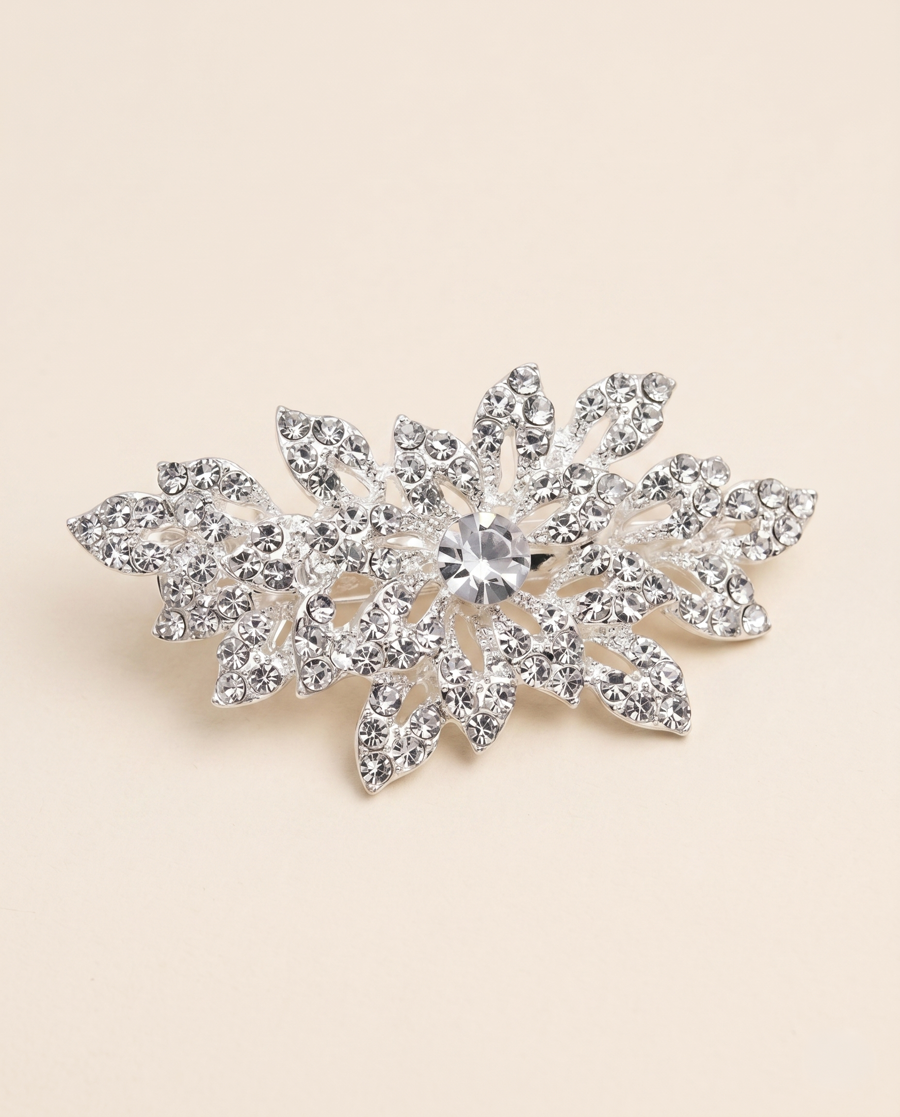 A sparkling crystal brooch with a central stone surrounded by intricate leaf-like designs.