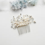 A decorative hair accessory with a comb and white pearls and crystals is displayed on a white background.