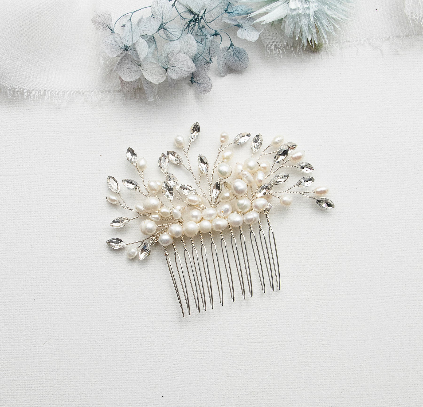 A decorative hair accessory with a comb and white pearls and crystals is displayed on a white background.