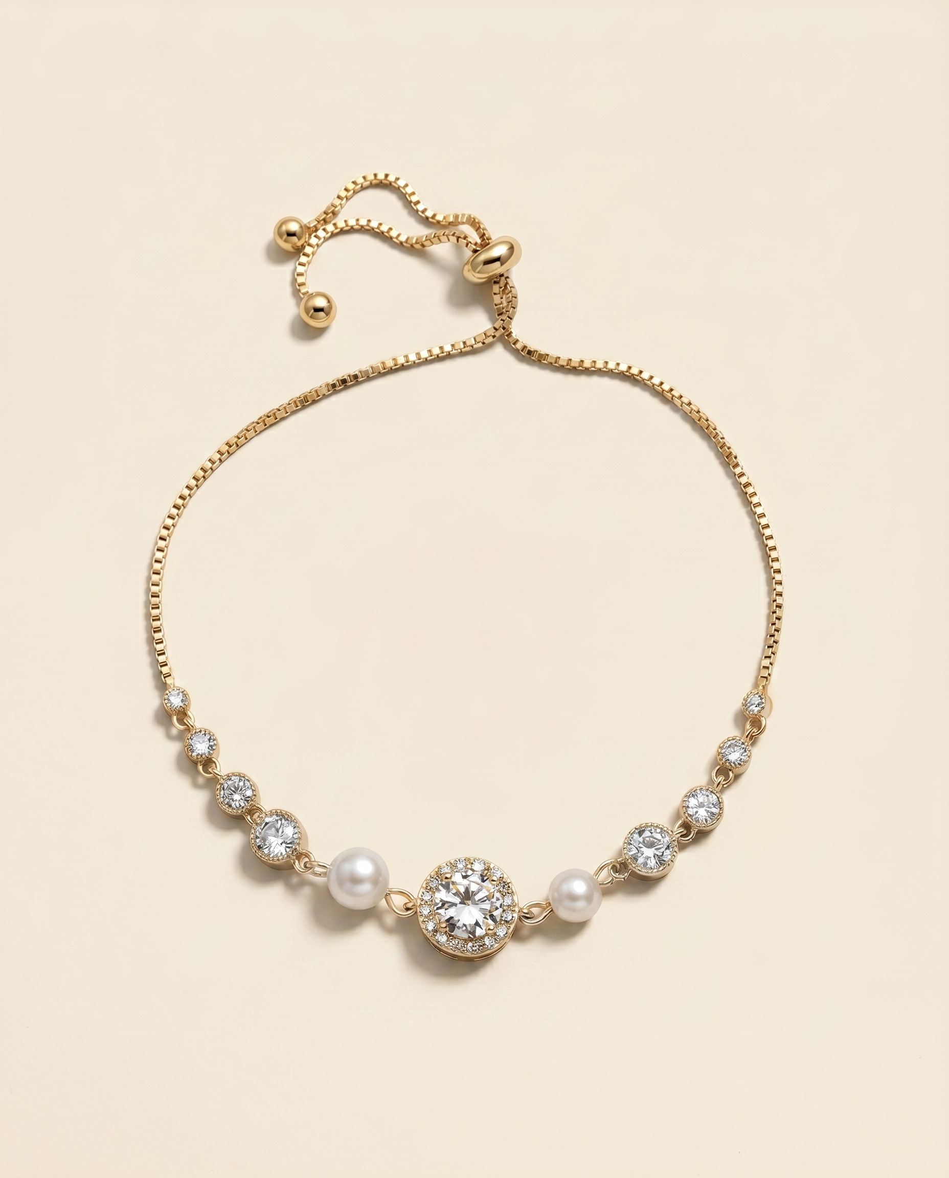 A gold-colored bracelet with a central pearl and a large crystal accent, set against a light beige background.