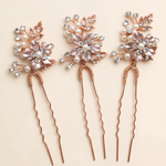 a set of three decorative hair clips with floral designs and sparkling gemstones.