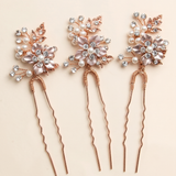 a set of three decorative hair clips with floral designs and sparkling gemstones.