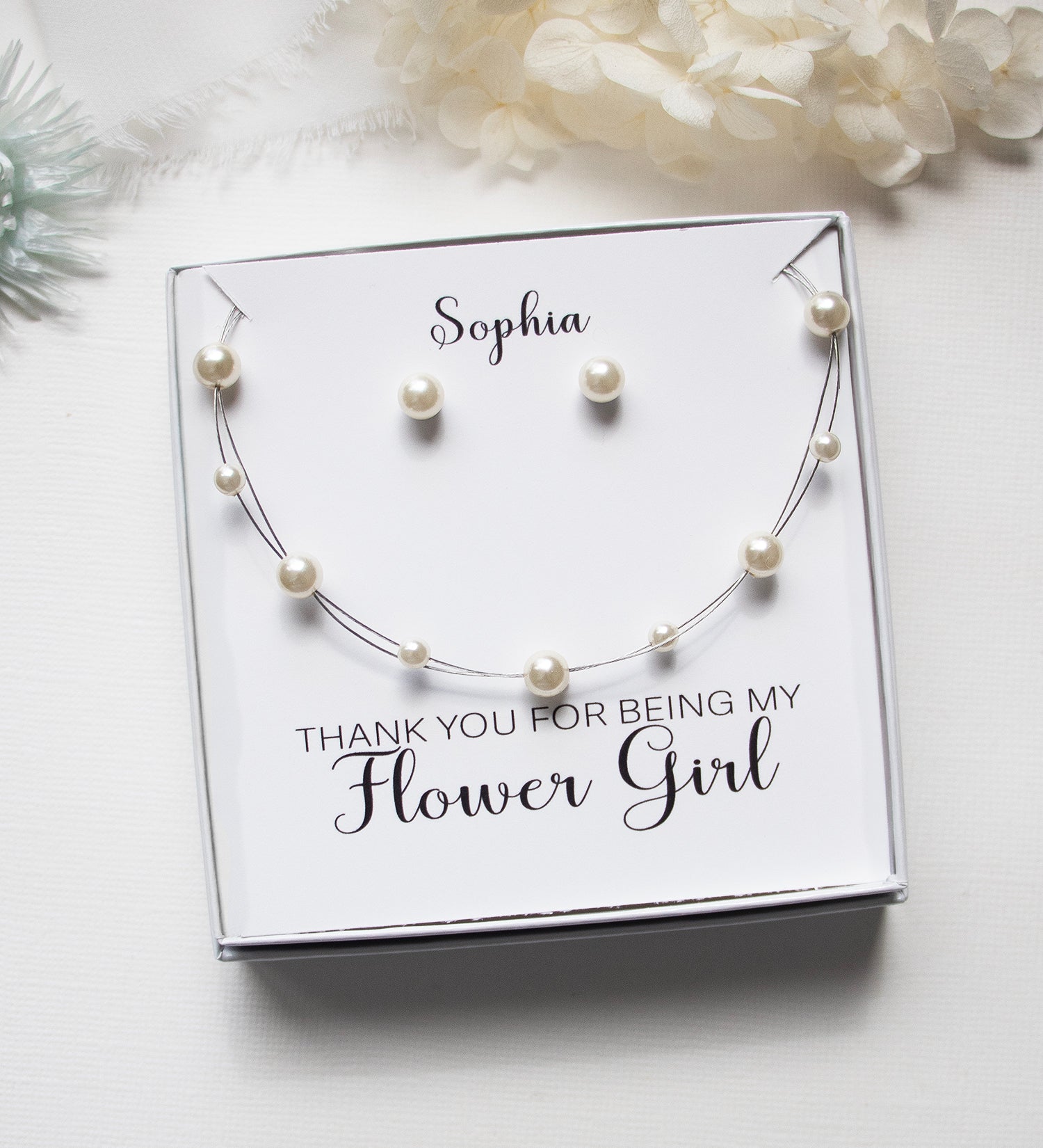 A gift box containing a necklace and earrings, with a personalized message on the box.