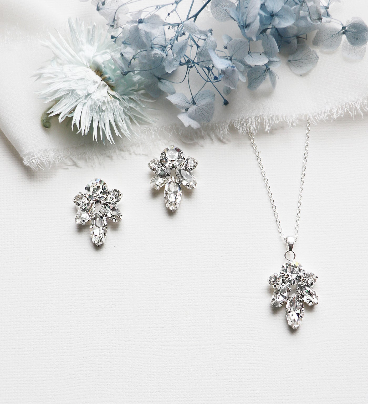 a necklace, earrings and a flower on a white surface