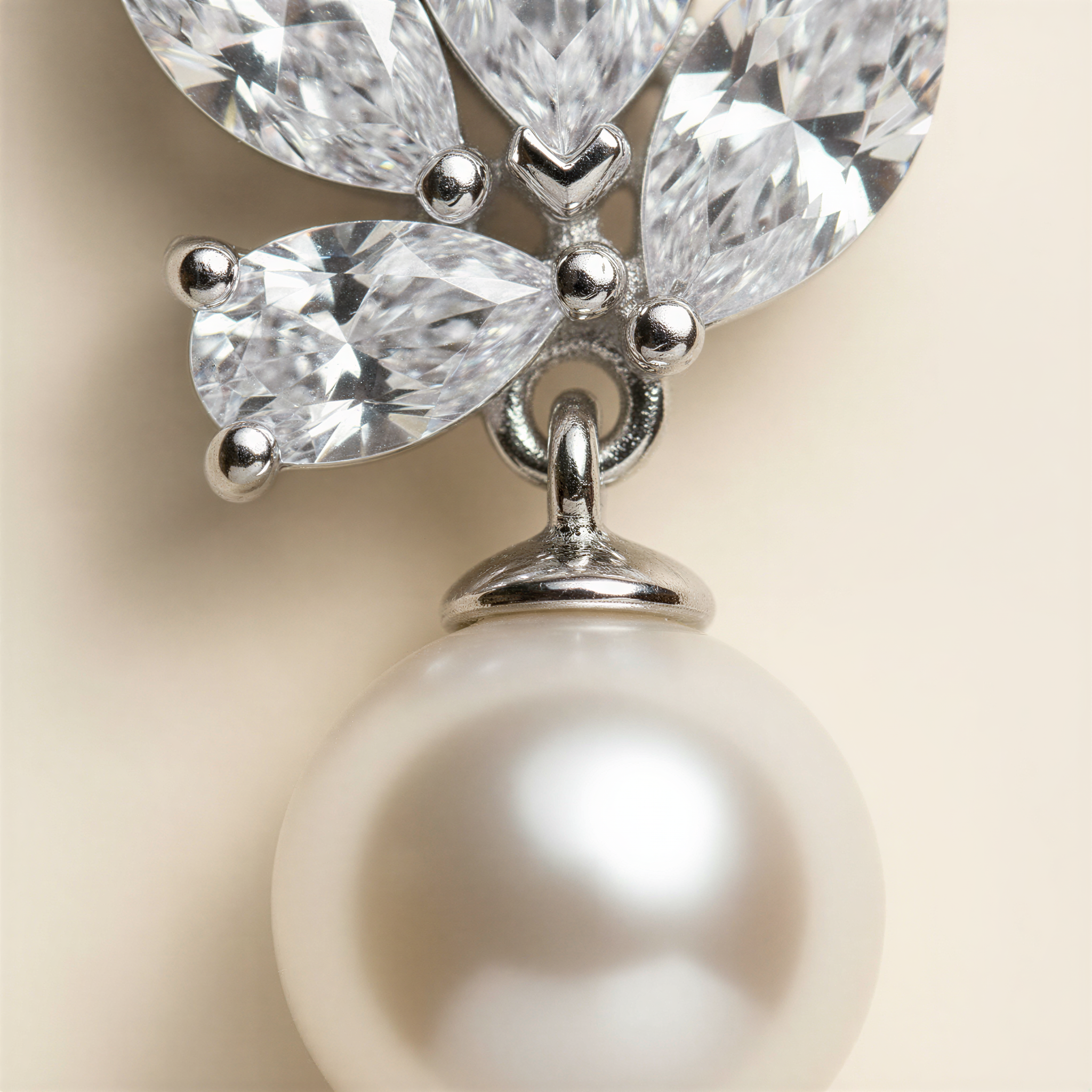 A close-up image of a pearl-like pendant with a silver clasp and a cluster of sparkling crystal gemstones attached to it.