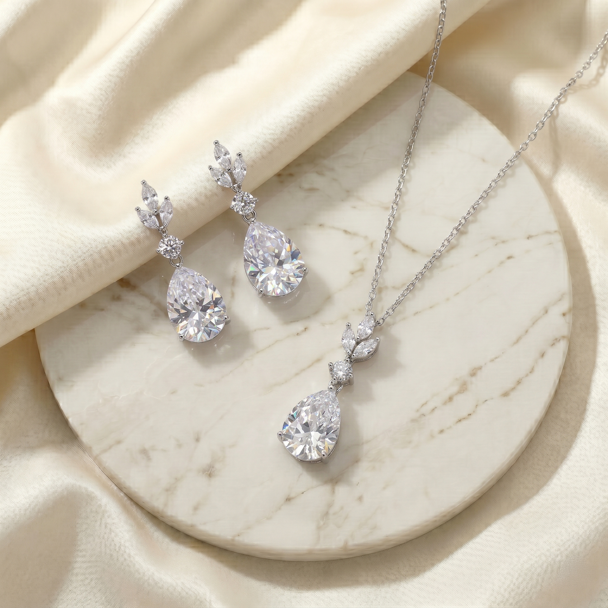 A necklace with a pendant and earrings with a dangling design are displayed on a marble surface.