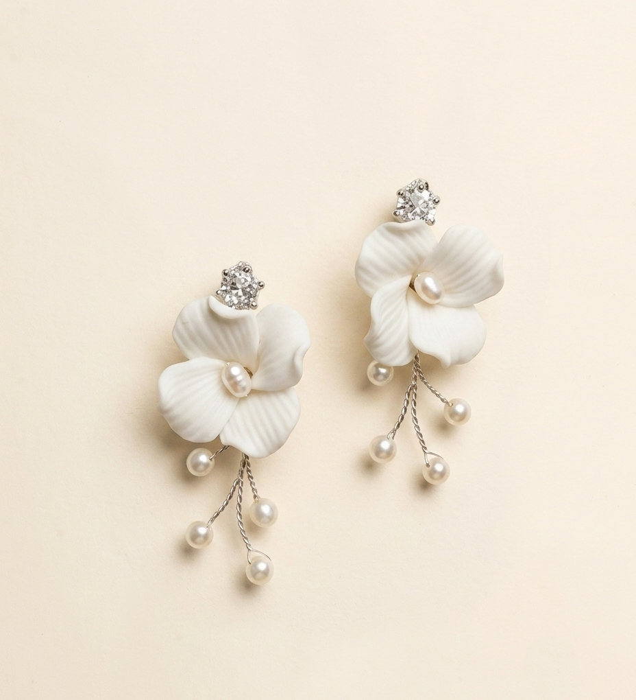 A pair of elegant white flower-shaped earrings with pearls and crystals.