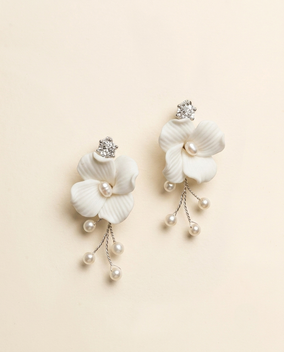 A pair of elegant white flower-shaped earrings with pearls and crystals.