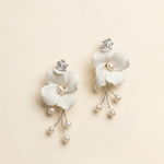 A pair of elegant white flower-shaped earrings with pearls and crystals.