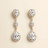 A pair of elegant gold earrings with three large pear-shaped gemstones set in a halo-like design.