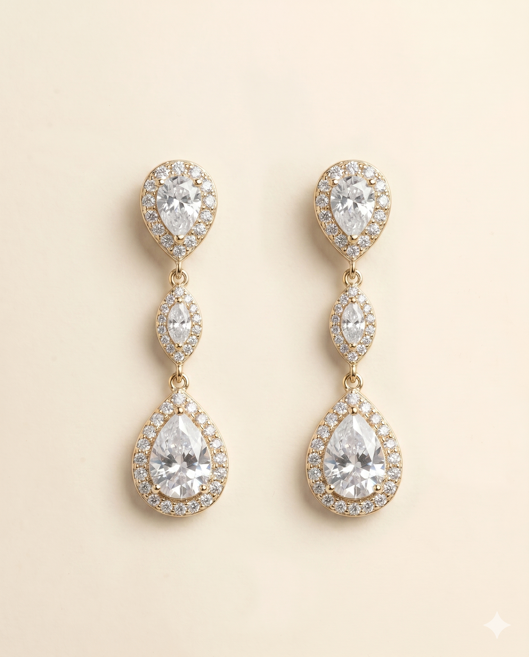 A pair of elegant gold earrings with three large pear-shaped gemstones set in a halo-like design.