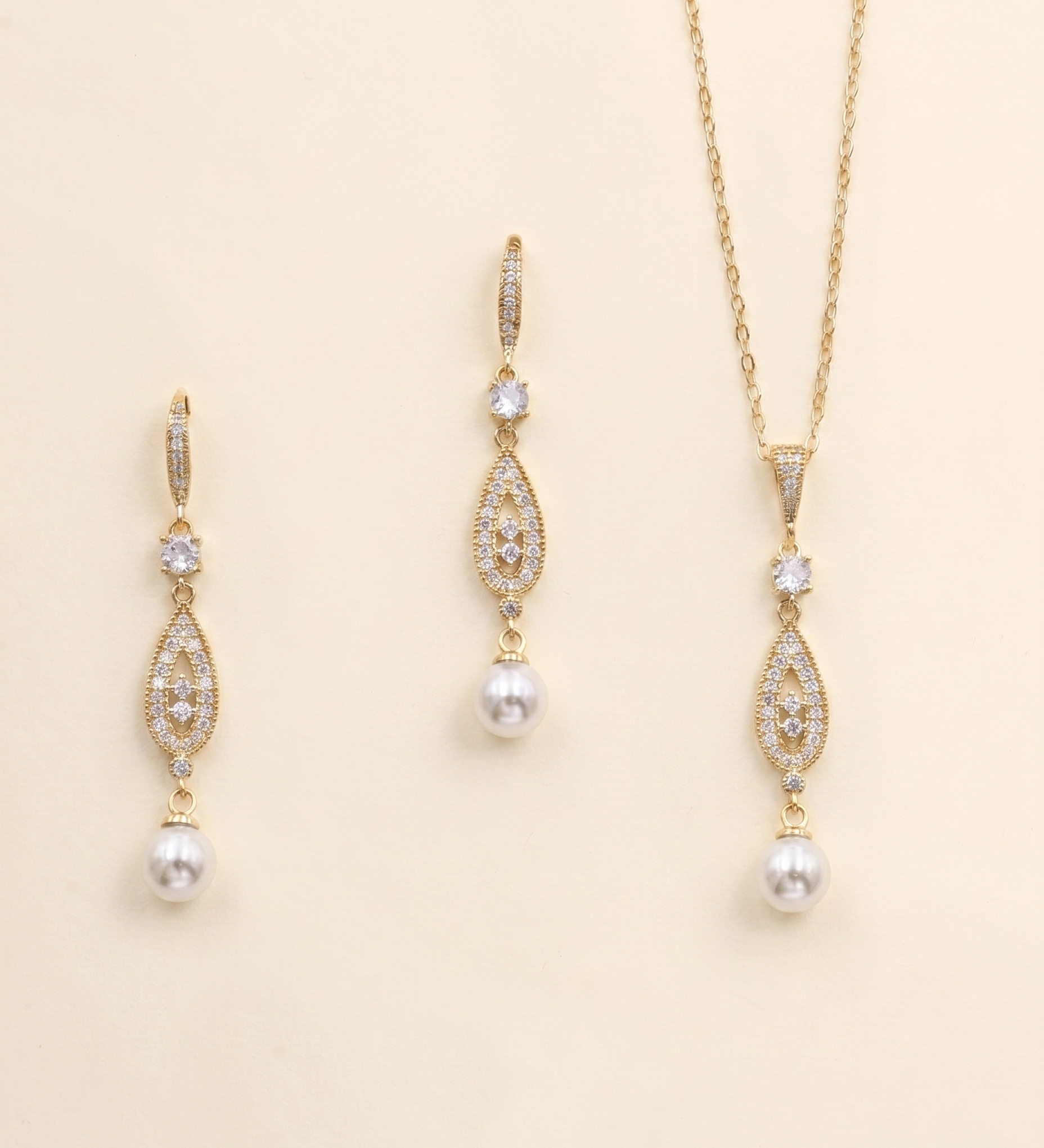 A set of three gold-colored jewelry pieces, including earrings and a necklace, with pearls and gemstones.