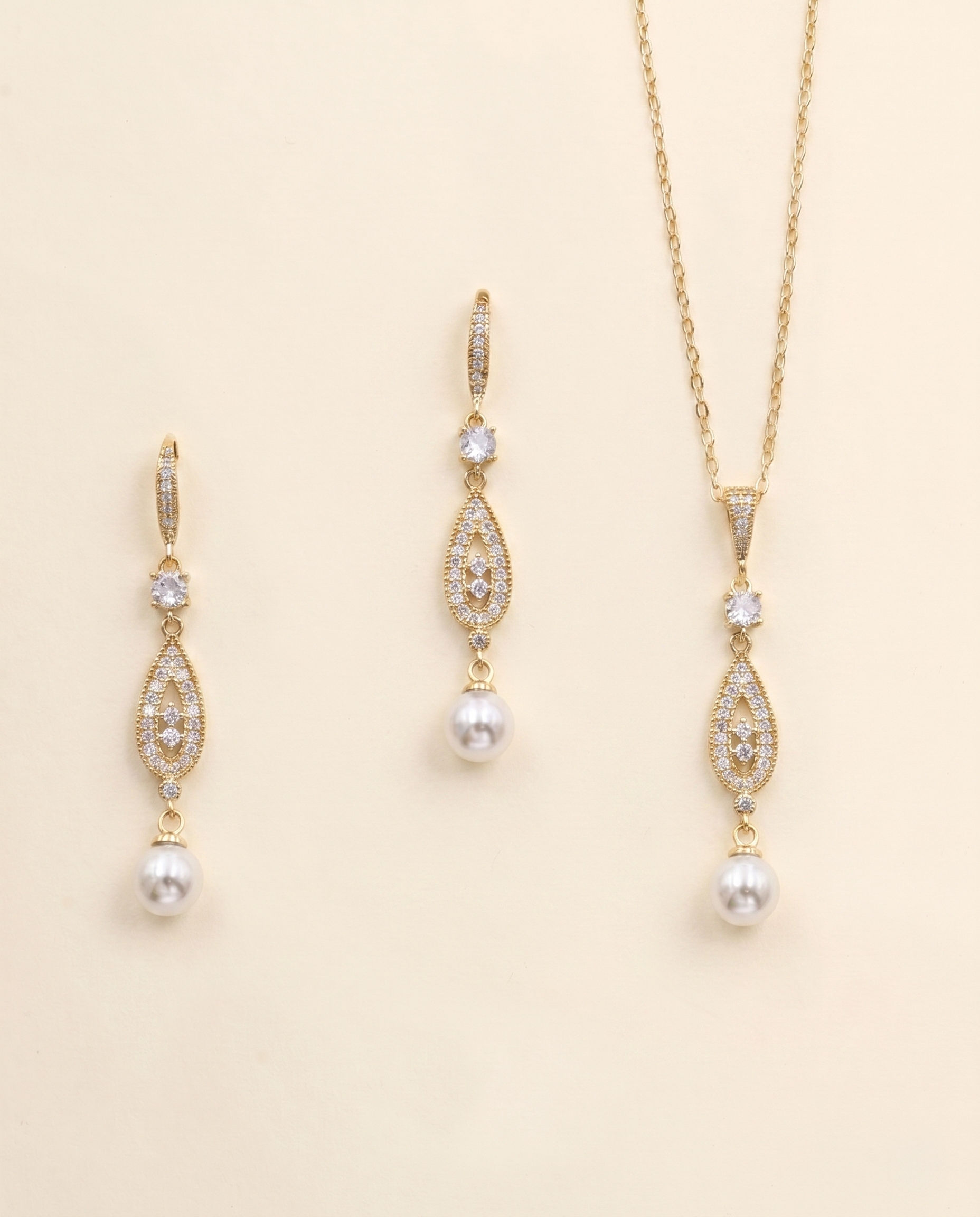 A set of three gold-colored jewelry pieces, including earrings and a necklace, with pearls and gemstones.