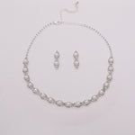 A necklace and earrings set made of silver and white pearls, arranged on a white background.
