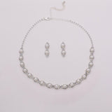 A necklace and earrings set made of silver and white pearls, arranged on a white background.