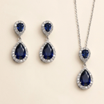 A pair of elegant earrings and a necklace featuring a combination of blue gemstones and sparkling diamonds.