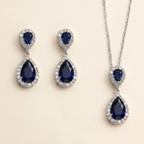 A pair of elegant earrings and a necklace featuring a combination of blue gemstones and sparkling diamonds.