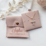 A necklace with a cross pendant and a small pouch with the name "Sophia" printed on it, along with some white flowers and a white fabric background.