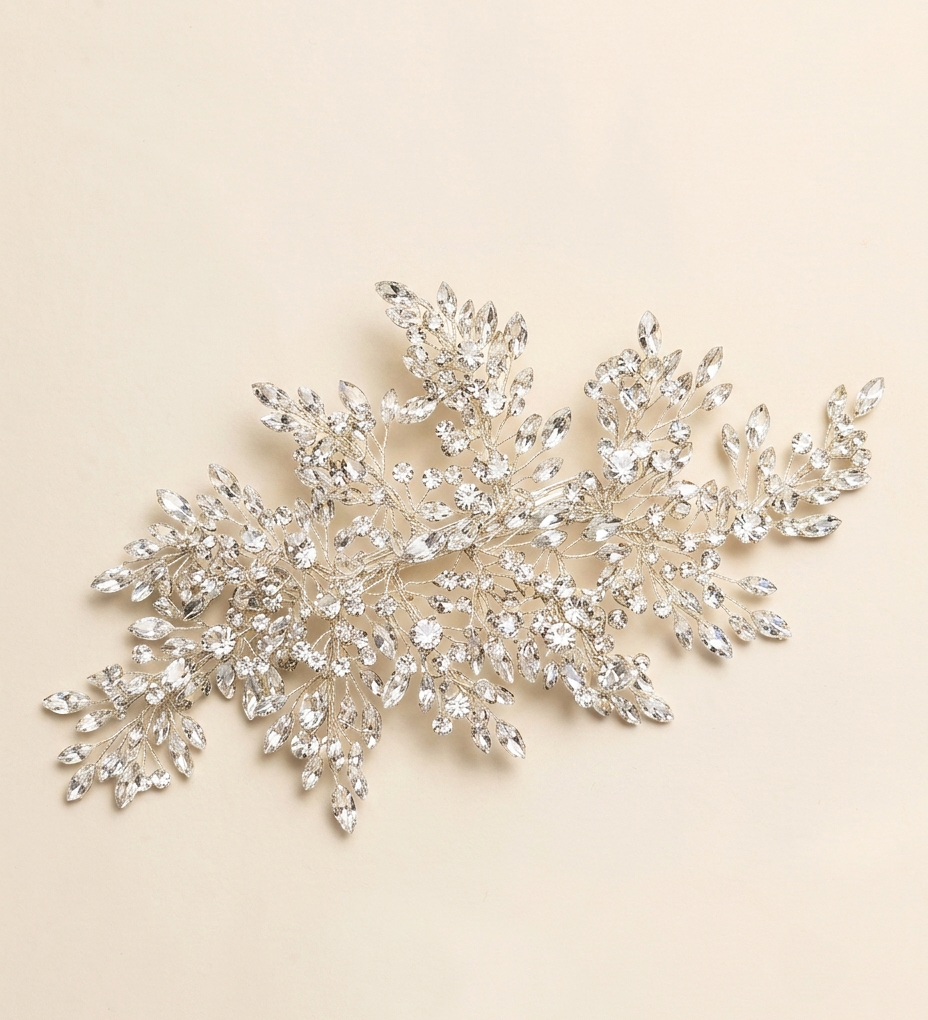 A decorative piece of jewelry with numerous small, sparkling crystal elements arranged in a floral or leaf-like design.