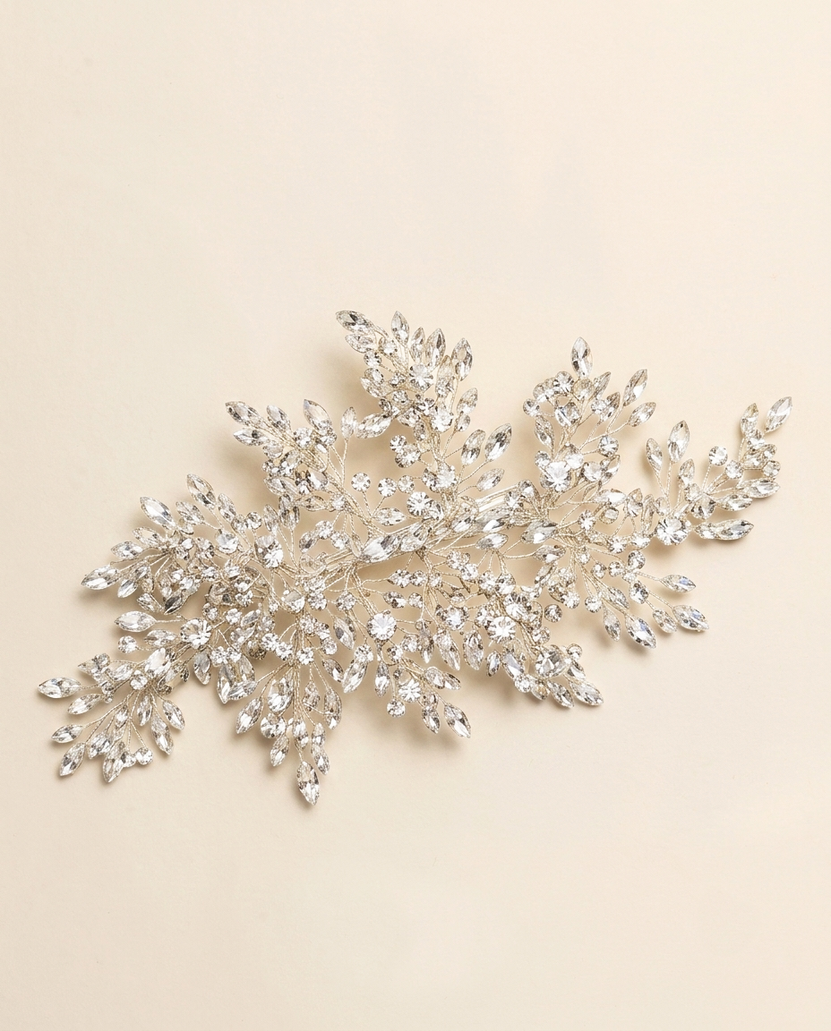 A decorative piece of jewelry with numerous small, sparkling crystal elements arranged in a floral or leaf-like design.