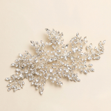 A decorative piece of jewelry with numerous small, sparkling crystal elements arranged in a floral or leaf-like design.