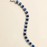 A bracelet with a row of blue gemstones, including diamonds, arranged in a decorative pattern.