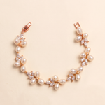 A delicate bracelet adorned with small pearls and crystal embellishments, resting on a light beige background.