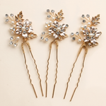 Three ornate hair pins with gold and crystal embellishments, arranged in a row.