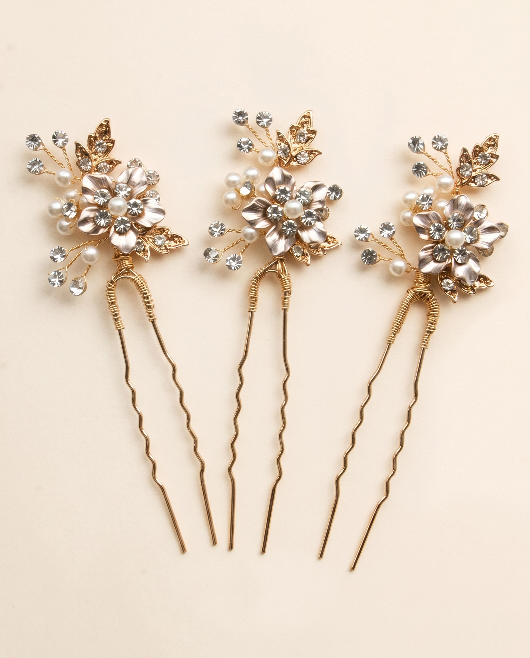 Three ornate hair pins with gold and crystal embellishments, arranged in a row.